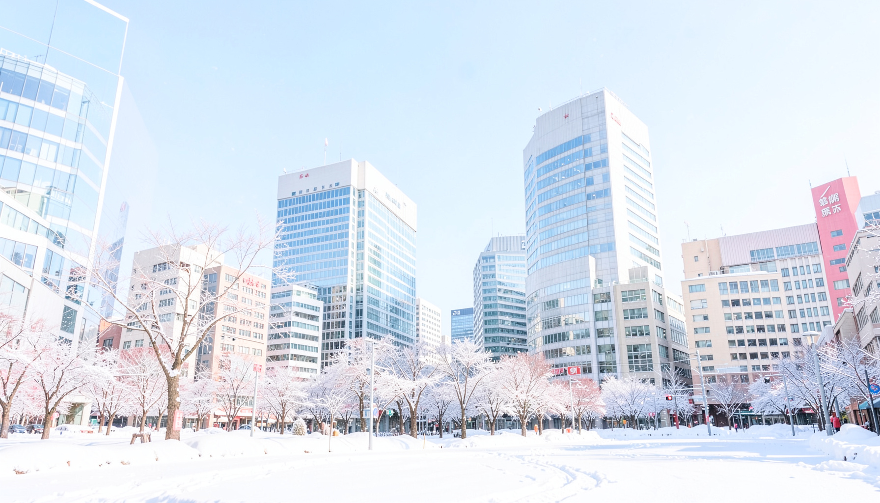 冬の札幌市の雪景色と近代的なオフィスビルが並ぶ街並み、澄んだ青空が広がる明るい昼間の風景